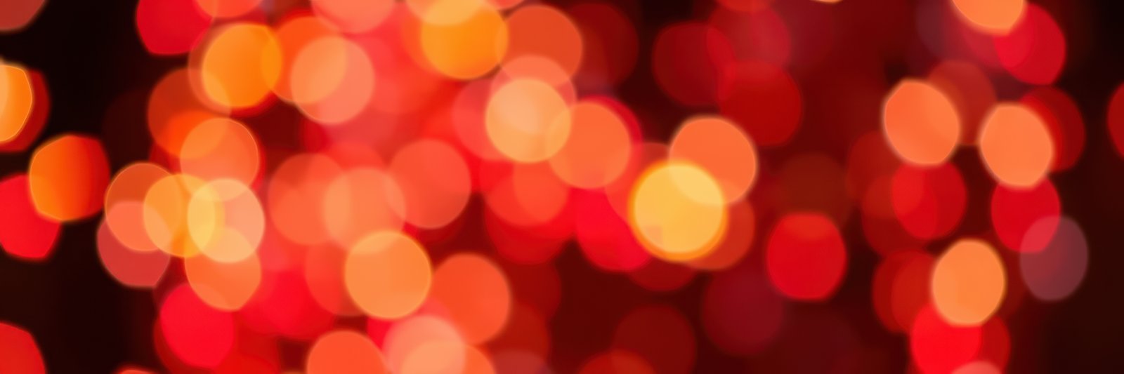 Bright red and orange bokeh lights create a warm, festive atmosphere during an evening celebration
